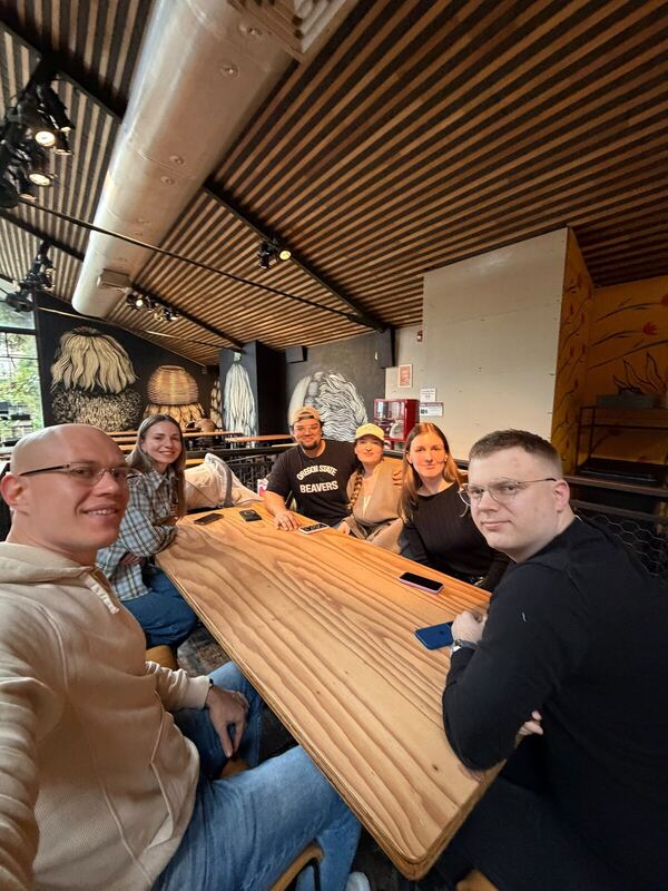 The same group seen from the head of the table, murals on the wall behind